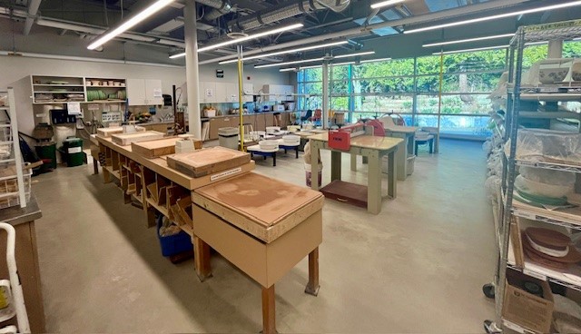 Interior of the pottery studio at the Delbrook Community Recreation Centre, showing the abundance of natural light from the large windows behind the wheels.