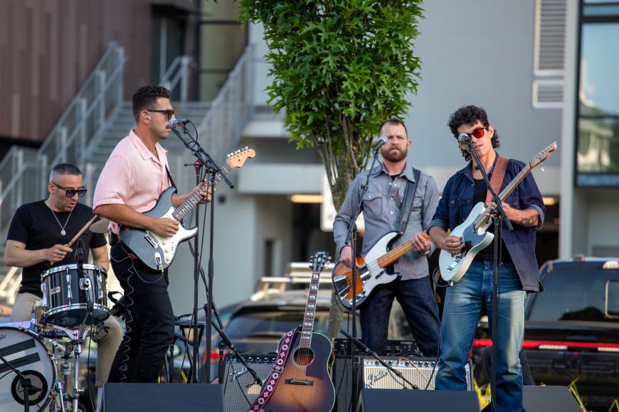 A band performs on a stage in front of a recreation centre. 