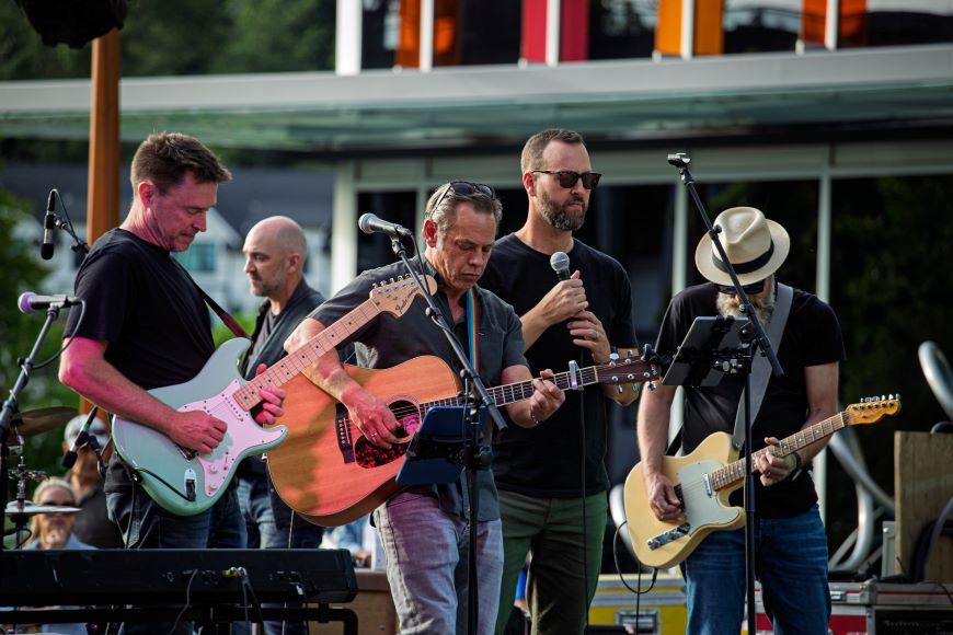 A band performs on a stage in front of a recreation centre. 