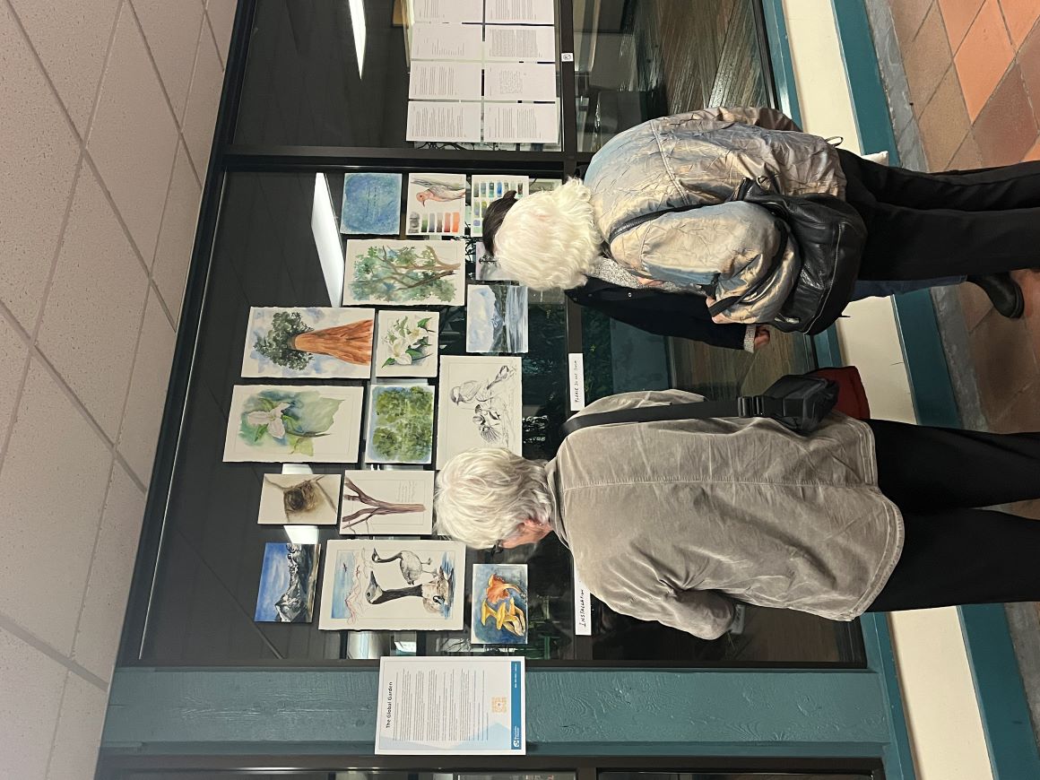 Two older adults admire a watercolour exhibit. 