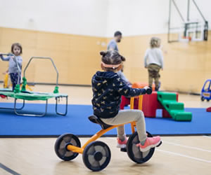 child on bike at parent participation indoor playground
