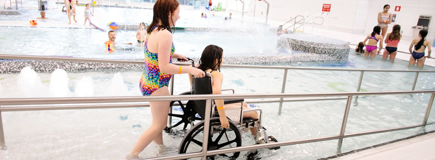 Girl in a wheelchair being wheeled into the pool