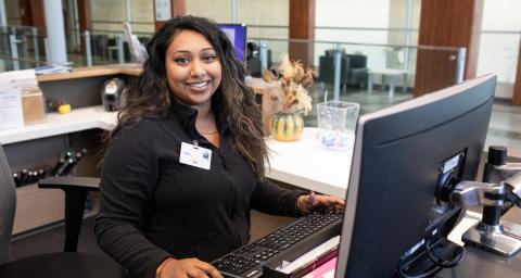 A woman stands at a computer at Delbrook front desk