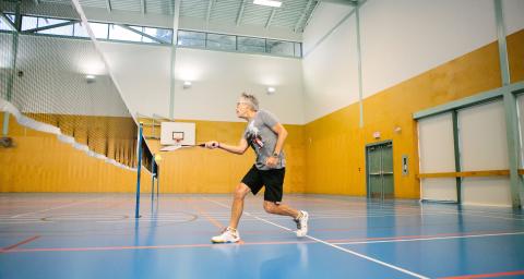 Man plays badminton in Parkgate gymnasium