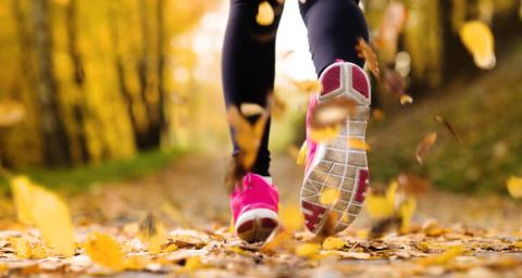 A woman runs through autumn leaves