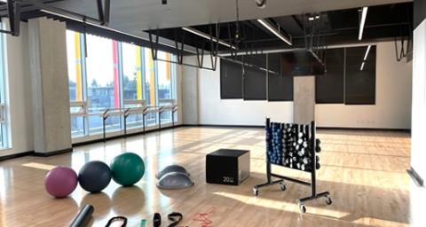 The workout studio at the Lions Gate Community Recreation Centre offers large windows and lots of natural light. Also pictured is the range of handheld fitness equipment available for studio workouts, including BOSU balls, foam rollers, resistance bands, and dumbbells.