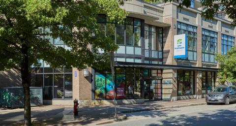 Exterior of the front entrance of the John Braithwaite Community Centre with trees and sidewalk and street in foreground.
