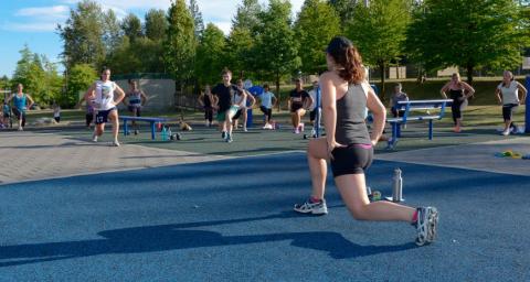 An NVRC instructor leads a group in an outdoor fitness class in a park.