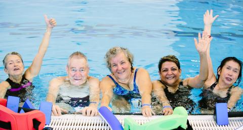 A group of seniors pose in the pool during an aquafit class