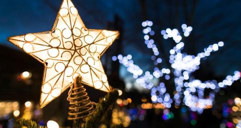 An illuminated start on top of a Christmas tree with Christmas lights in Lynn Valley Village in the background. 