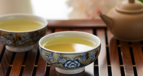 Two tea cups and a tea pot on a wooden tray