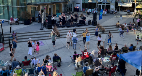 A crowd enjoys an oven air concert in a busy public plaza. 