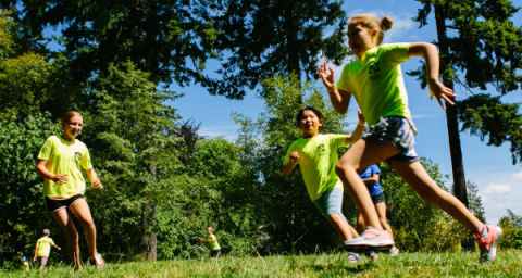 A group of children play tag in a park. 