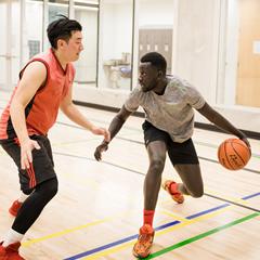Two men playing basketball at Lions Gate Community Recreation Centre