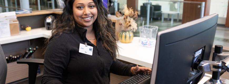 A woman stands at a computer at Delbrook front desk