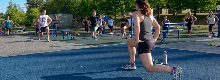 An NVRC instructor leads a group in an outdoor fitness class in a park.