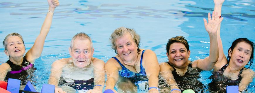 A group of seniors pose in the pool during an aquafit class