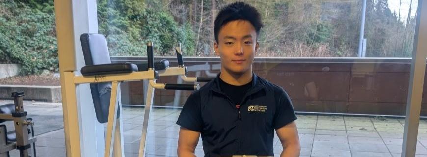 A practicum student holding a clip board and wearing an NVRC vest works in the Delbrook Fitness Centre.