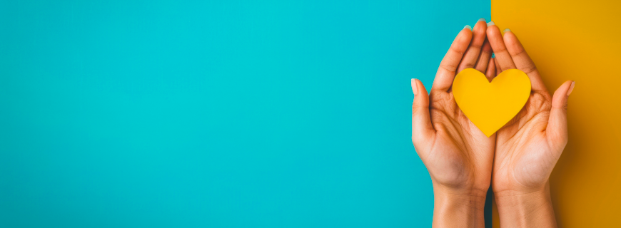 A pair of hands holding a yellow paper heard against a turquise and yellow background